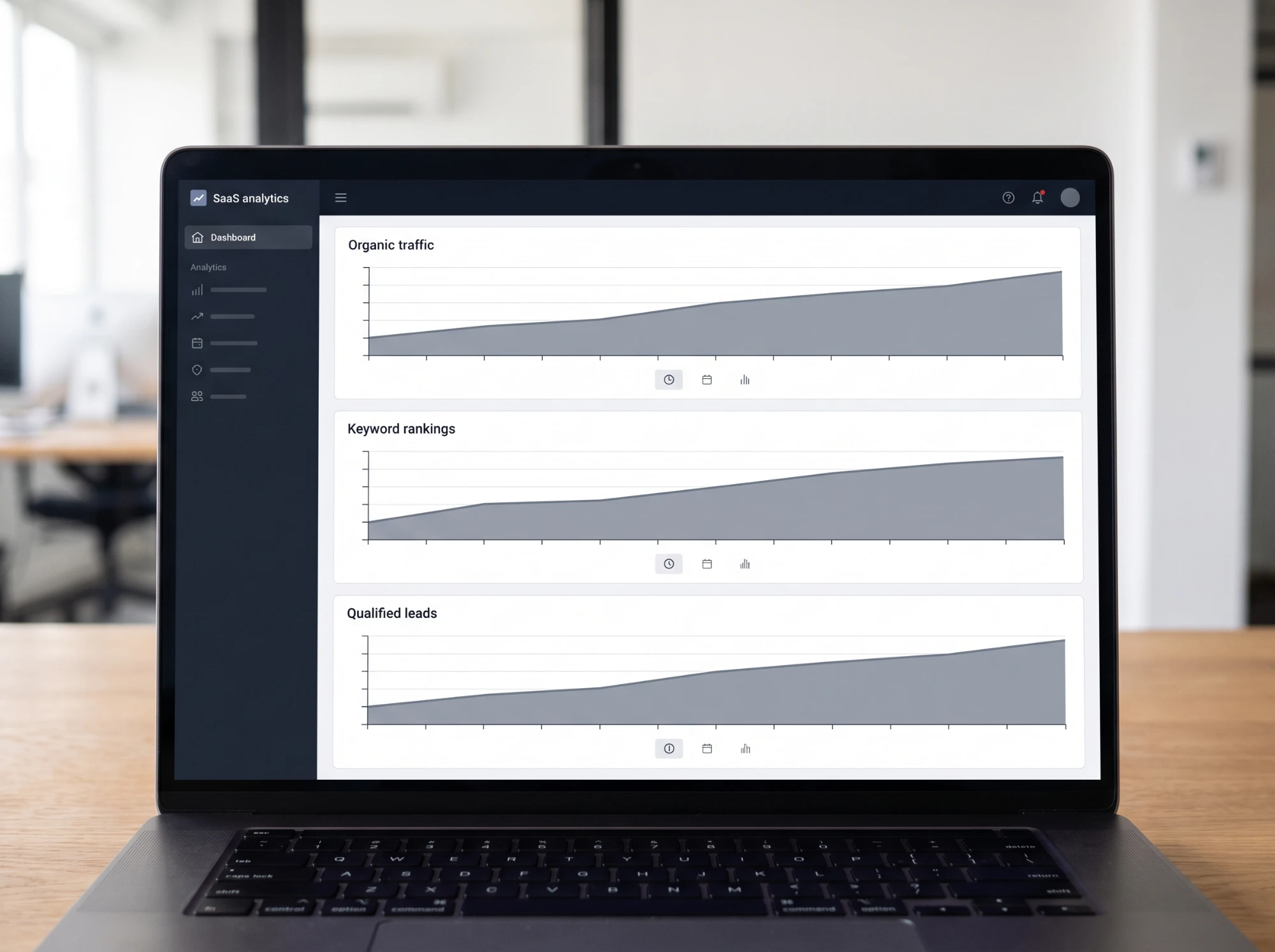 A laptop showing an analytics dashboard with organic traffic, keyword rankings and qualified leads trending upward